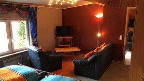 A living room with a sofa, a television, and a table. - Quiet Holiday home in the middle of the Volcano Eifel (Rheinland-Pfalz)