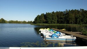 Ein ruhiger See mit mehreren kleinen Booten, die an einem hölzernen Steg vertäut sind.