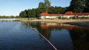 Ein Ufergrundstück mit Steg, Schwimmbereich und einem Gebäude mit rotem Dach.