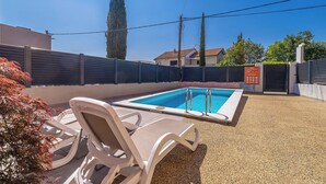 Une piscine avec des chaises longues, un espace délimité par une clôture et un ciel dégagé.