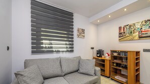 Un salon avec un canapé gris, un meuble en bois et un tableau accroché au mur.