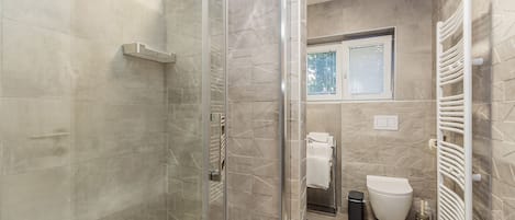 Een douche, handdoeken, zeep, toiletpapier