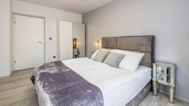 Une chambre à coucher avec un lit, des tables de chevet, une armoire et une porte.