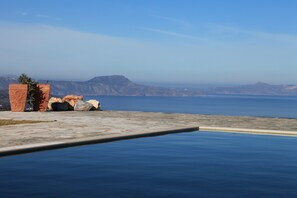 Ein Pool mit freiem Blick auf das Meer und ferne Berge.