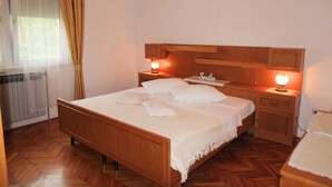 A neatly arranged bedroom with a wooden bed, two bedside tables with lamps, a headboard, and a window with curtains. - Cozy 3-Bedroom Haven, Perfect for 5, With Parking Space (Ližnjan)