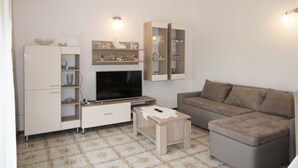 A living room with a TV, sofa, cabinet, and patterned floor. - Cozy 3-Bedroom Haven, Perfect for 5, With Parking Space (Ližnjan)