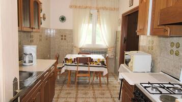 A compact kitchen with wooden cabinets, a gas stove, a microwave, and a dining table with chairs.