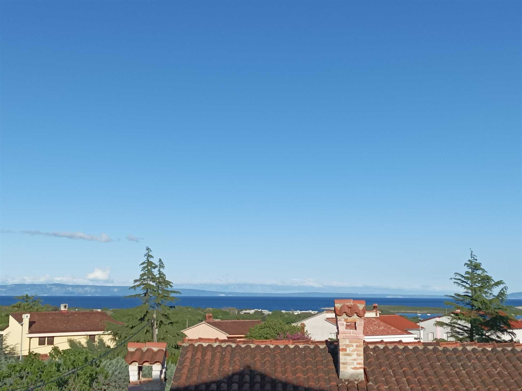 Un barrio residencial con casas, cielo azul despejado y vista al mar.