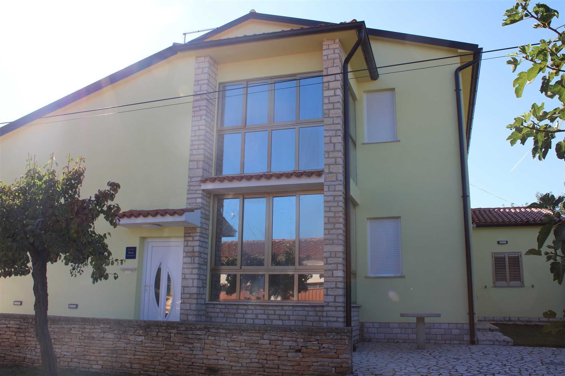 A two-story building with a stone facade, large windows, and a tiled roof.