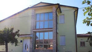 A two-story building with a stone facade, large windows, and a tiled roof. - Cozy 3-Bedroom Haven, Perfect for 5, With Parking Space (Ližnjan)