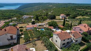 Un barrio residencial con casas, piscina y vistas al mar y a las colinas.