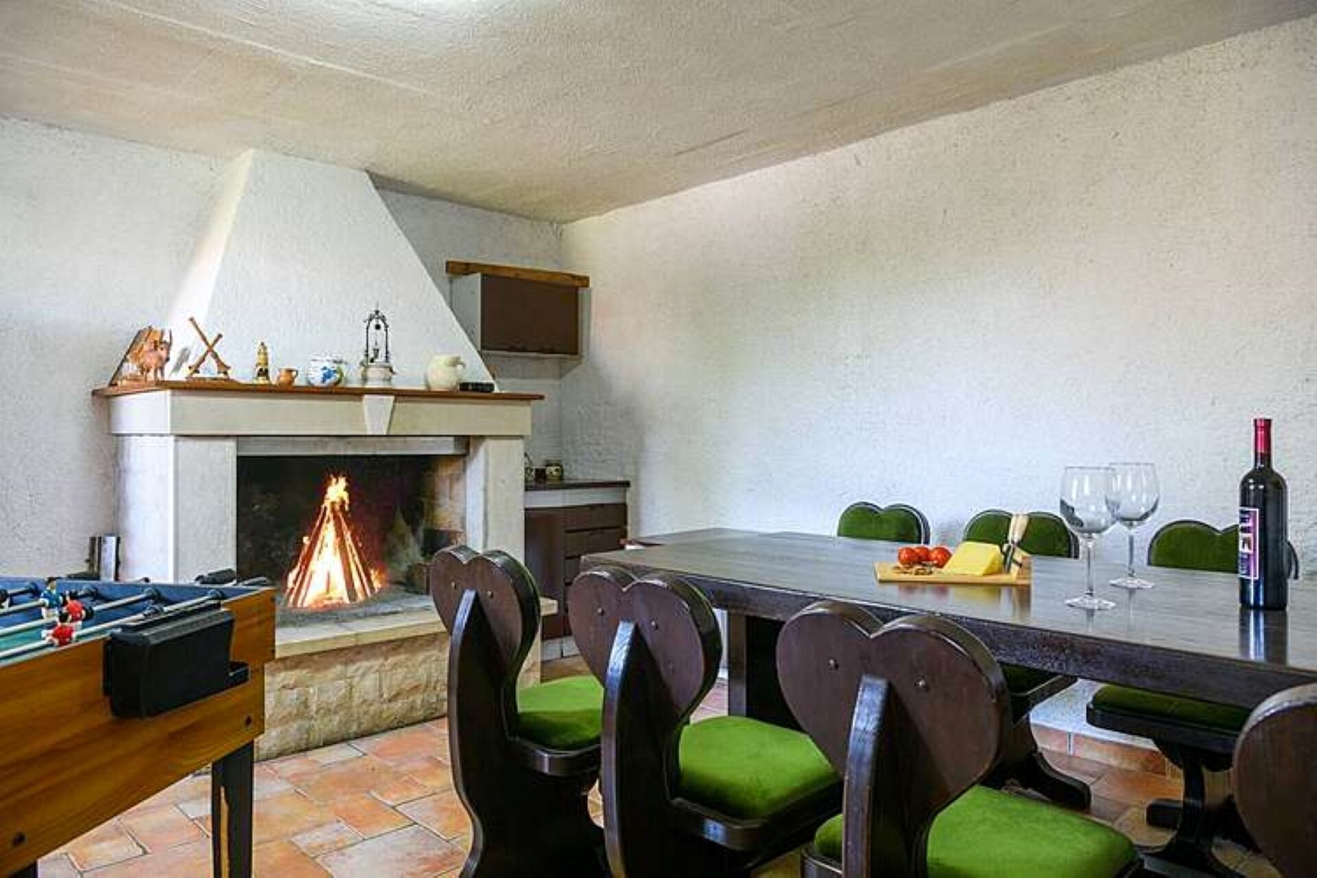 Comedor con chimenea, sillas tapizadas en verde, mesa de billar y una mesa lista para una comida.