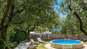 Un patio trasero con piscina, sillas de descanso y una hamaca.