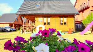 Eine Holzhütte mit geneigtem Dach, einer kleinen Veranda und einem Schild, das anzeigt, dass es sich um ein Gästehaus handelt.