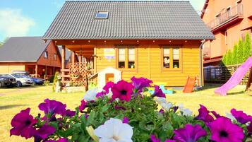Une cabane en bois avec un toit en pente, une petite véranda et une enseigne indiquant qu’il s’agit d’une maison d’hôtes.