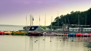 Ein Yachthafen mit verschiedenen Booten und einer Reihe bunter Autos, die am Wasser geparkt sind.
