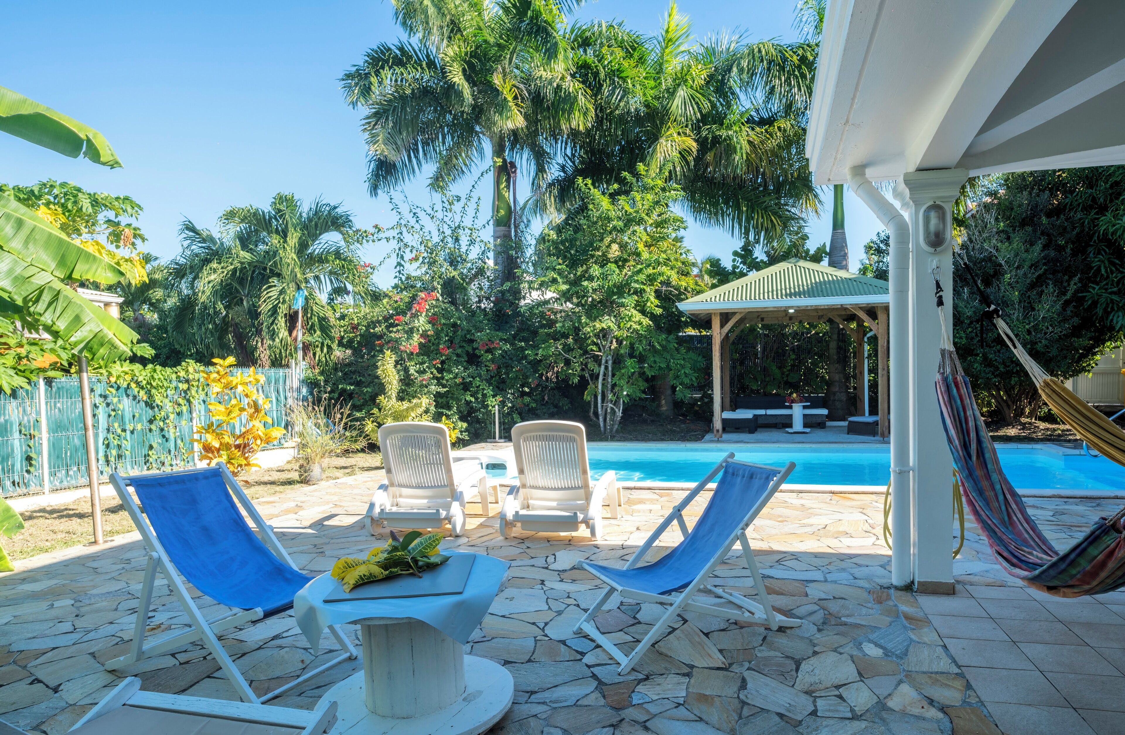 A poolside area with lounge chairs, a hammock, and a covered seating area.