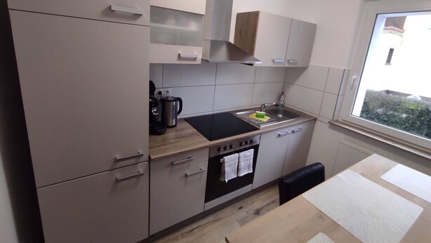 Cozinha moderna com forno embutido, pia e janela com vista para o exterior.