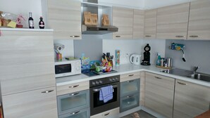 Una cocina moderna con armarios de madera clara, electrodomésticos de acero inoxidable y diversos utensilios de cocina sobre las encimeras.