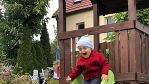 Niño en un tobogán de madera en un jardín.