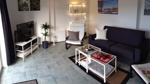 Una sala de estar moderna con un sofá, un sillón, una mesita de centro, un mueble para la televisión y objetos decorativos.