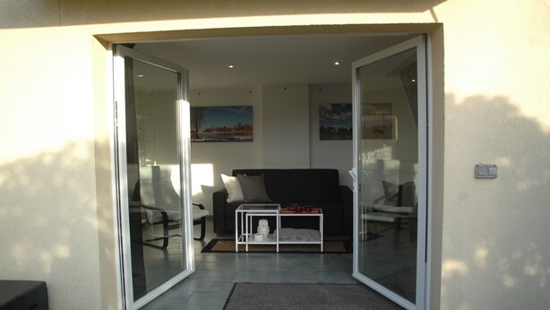Una sala de estar con sofá, mesa de centro y puerta de vidrio que da a un espacio exterior.