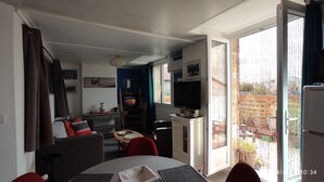 A compact living space with a dining area, a TV, and a balcony with a view. - Les Bonbonières d'Andréa Gavinies Pellegrin Furnished 2* T2 + private roof top 24 sq.m. (Bordeaux)