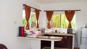A compact kitchen with a sink, a coffee maker, a microwave, and a refrigerator.