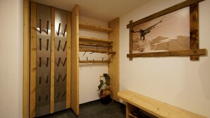 A wooden bench, a wall-mounted coat rack, and a framed picture of a bird.