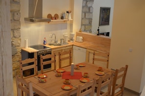 Cozinha compacta com fogão, pia e mesa de jantar de madeira para quatro pessoas.