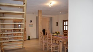 A wooden dining area with a table and chairs, a wooden staircase, and a door leading to another room. - Vacation home at the Bärenstein for 2-8 persons with 140 m² living space, sauna (Struppen)