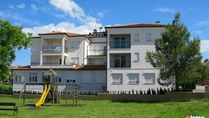 A multi-story building with a playground area, including a slide, and a sign indicating it is for sale. - 2-4 persons, modern furnishings, air-conditioned, washing machine (Porec)