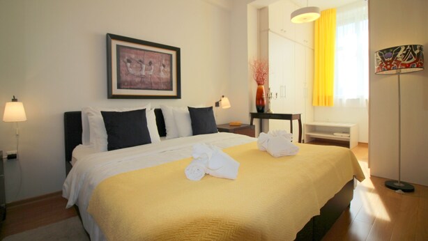 A neatly made bed with a yellow bedspread, white pillows, and a framed picture above it. - 2-4 persons, modern furnishings, air-conditioned, washing machine (Porec)