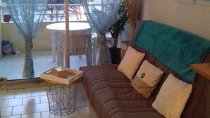 Una sala de estar con un sofá marrón, una mesita y vistas al balcón exterior.