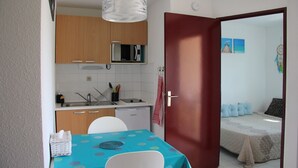 Una habitación pequeña con kitchenette, comedor y cama.