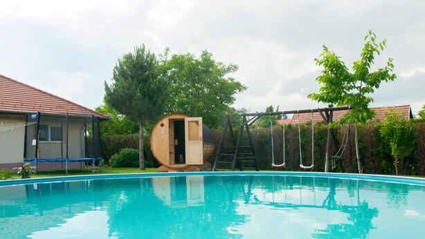 A swimming pool with a wooden structure and a swing set.