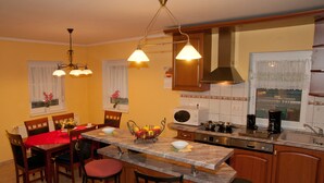 A kitchen with wooden cabinets, a marble countertop, and a dining area with a red tablecloth.