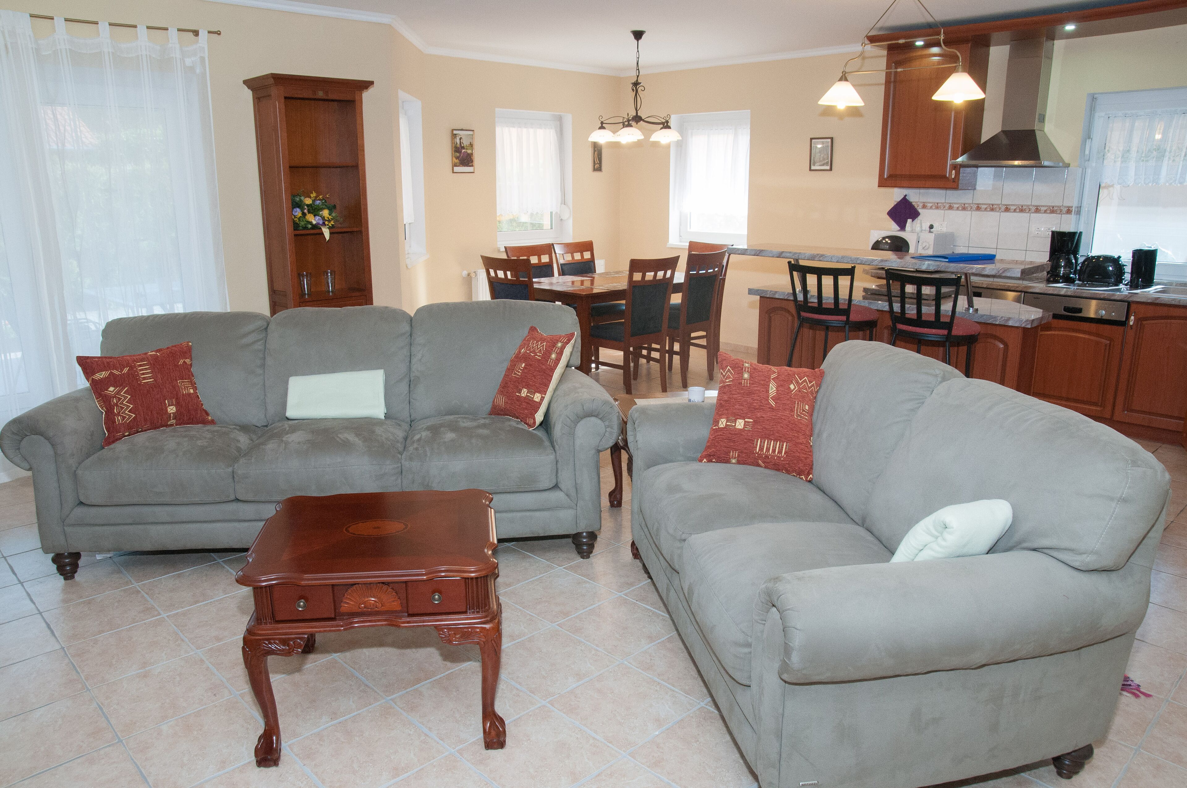 A living room with two grey sofas, a wooden coffee table, and a dining area with a table and chairs.