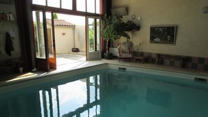 A swimming pool with a view of the outside. There is a chair and a potted plant near the pool. - Country house with private indoor  pool, dream garden near the Loire Vallylley (Dercé)
