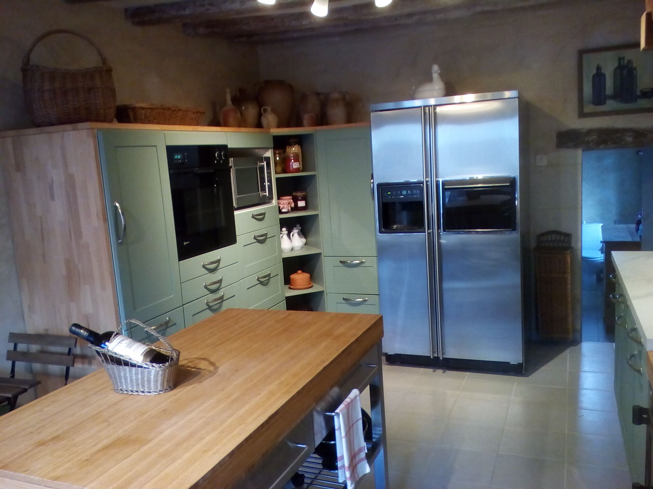 A kitchen with a wooden countertop, a stainless steel refrigerator, and a microwave.