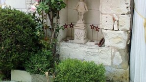 A stone wall with a statue of a woman and a rose bush climbing over it. - Country house with private indoor  pool, dream garden near the Loire Vallylley (Dercé)
