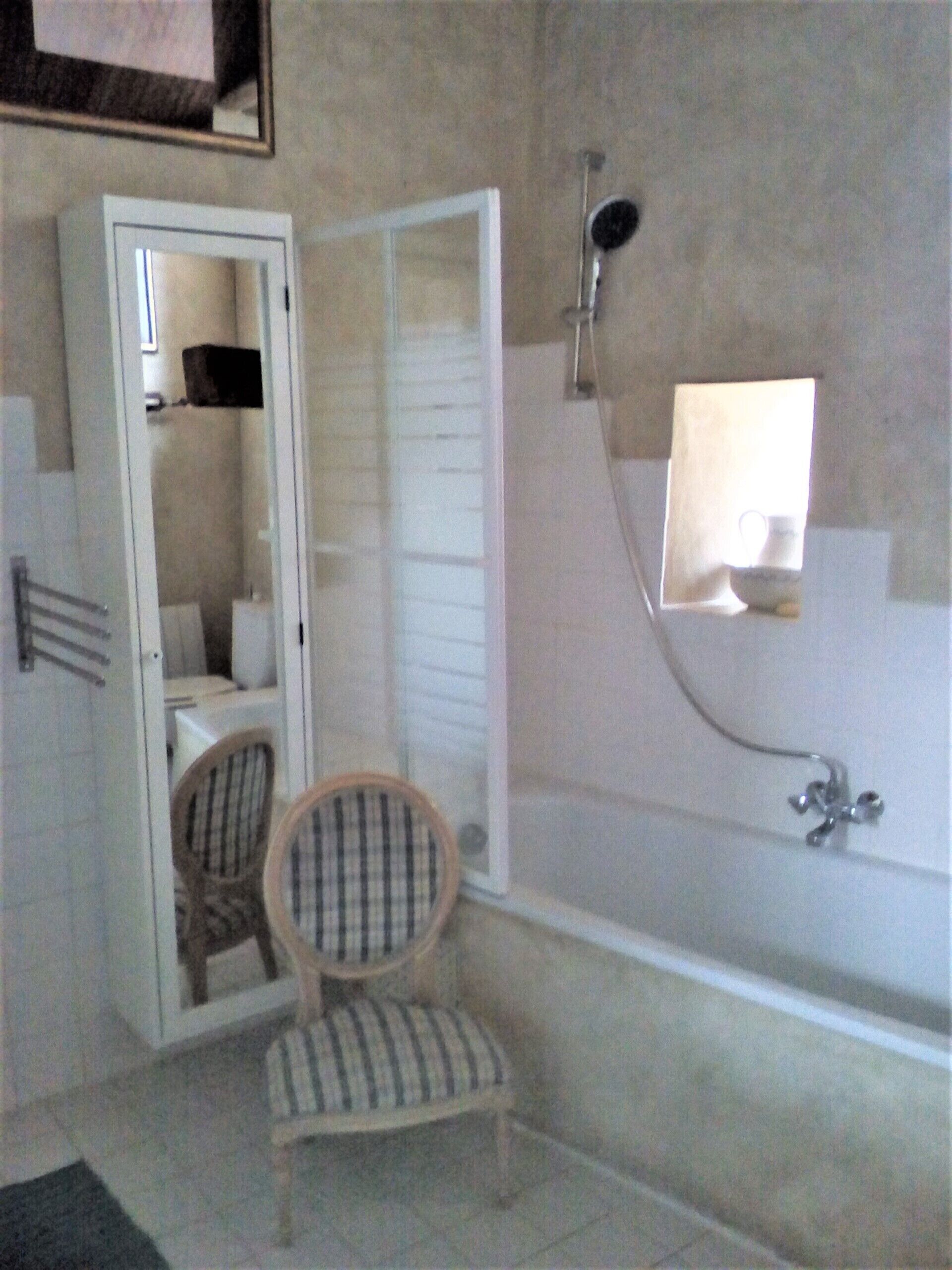 A bathroom with a bathtub, a shower, a chair, and a mirror.
