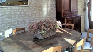 A dining area with a round wooden table surrounded by wooden chairs with white cushions. A large wooden cabinet is against the wall, and a chandelier hangs above the table. - Country house with private indoor  pool, dream garden near the Loire Vallylley (Dercé)