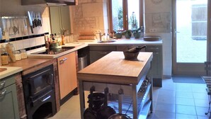 A kitchen with a wooden countertop, a sink, and a stove. There are potted plants on the windowsill and a clock on the wall. - Country house with private indoor  pool, dream garden near the Loire Vallylley (Dercé)