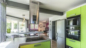 Una cocina moderna con una isla central, electrodomésticos de acero inoxidable y armarios verdes.