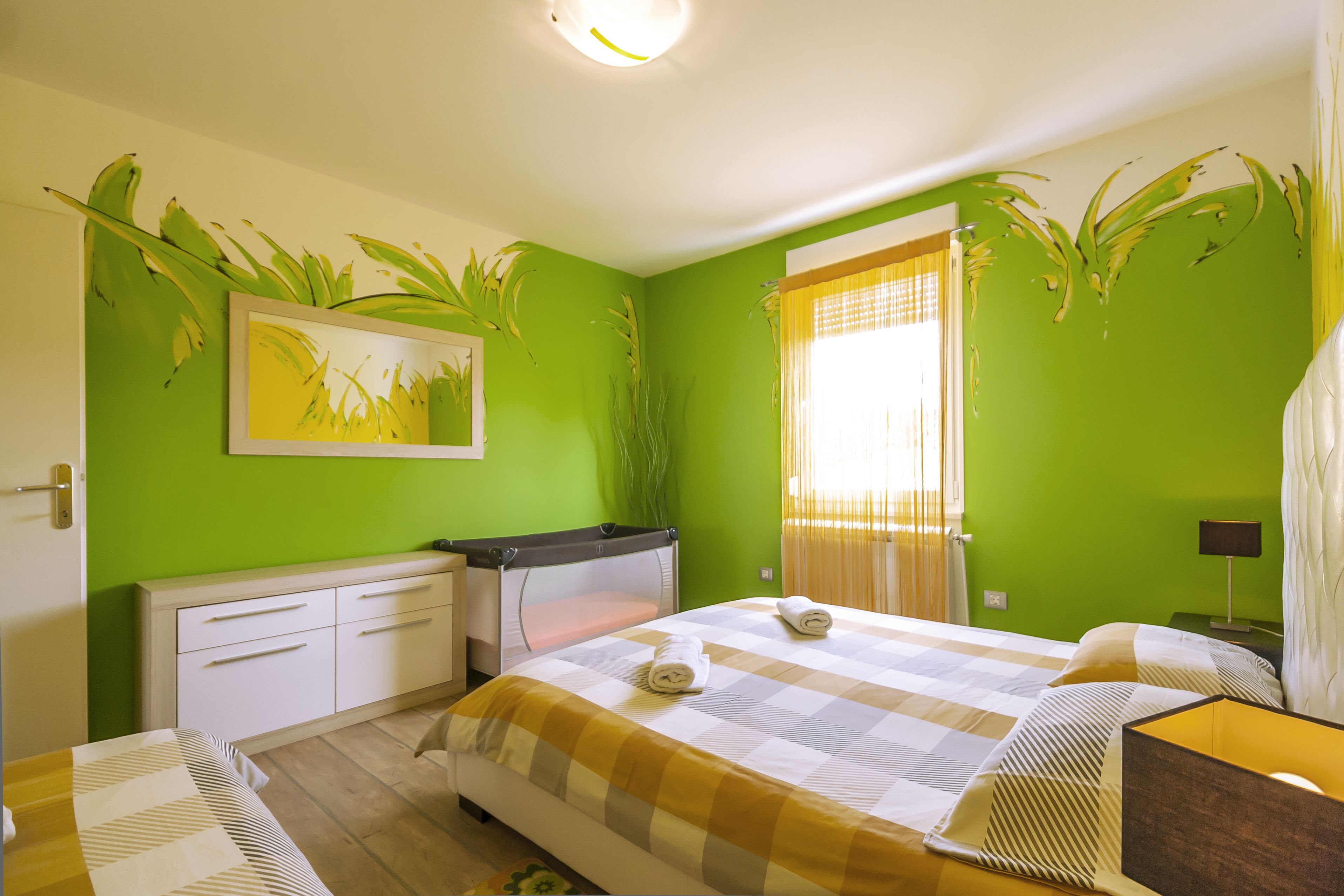 A room with a bed, a desk, and a window with curtains.