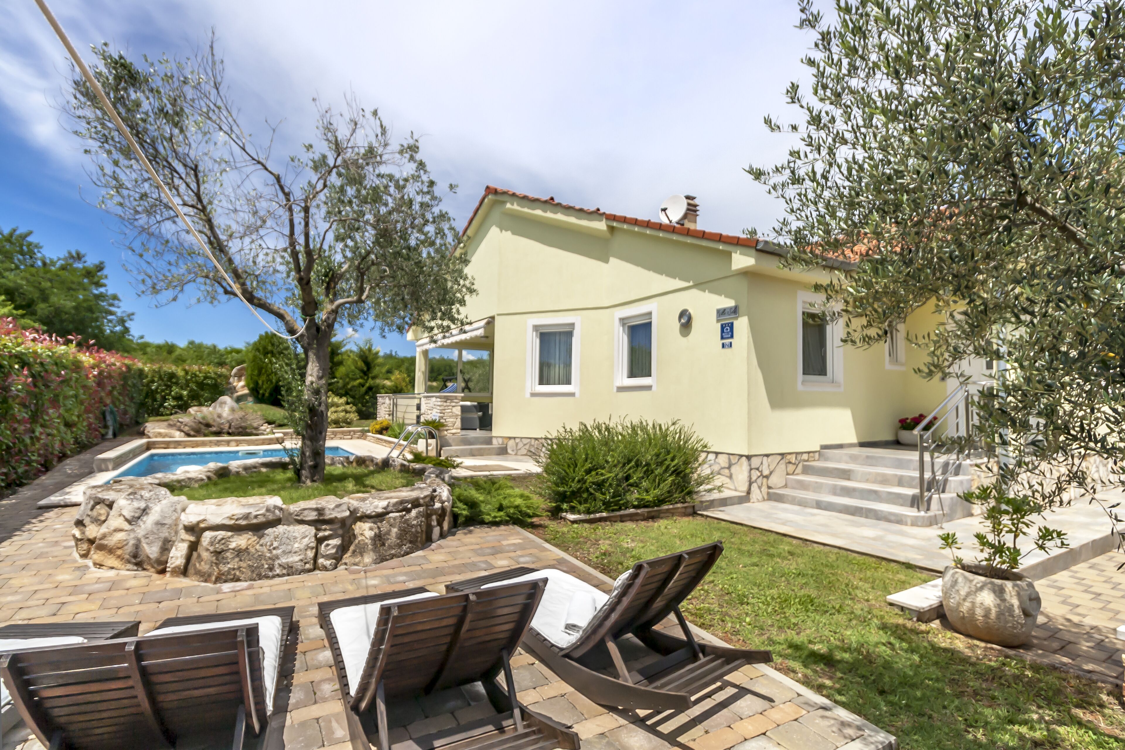 A house with a swimming pool, outdoor seating, and a garden.