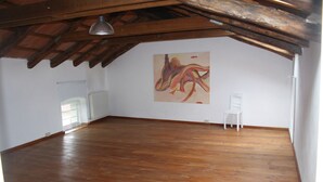Una habitación amplia con suelo de madera, un radiador blanco y una silla blanca.