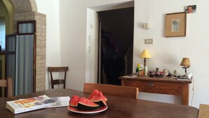Un comedor con una mesa de madera, un plato de sandía en rodajas y un libro titulado 'Every Day Magic' de Cassandra Carter.