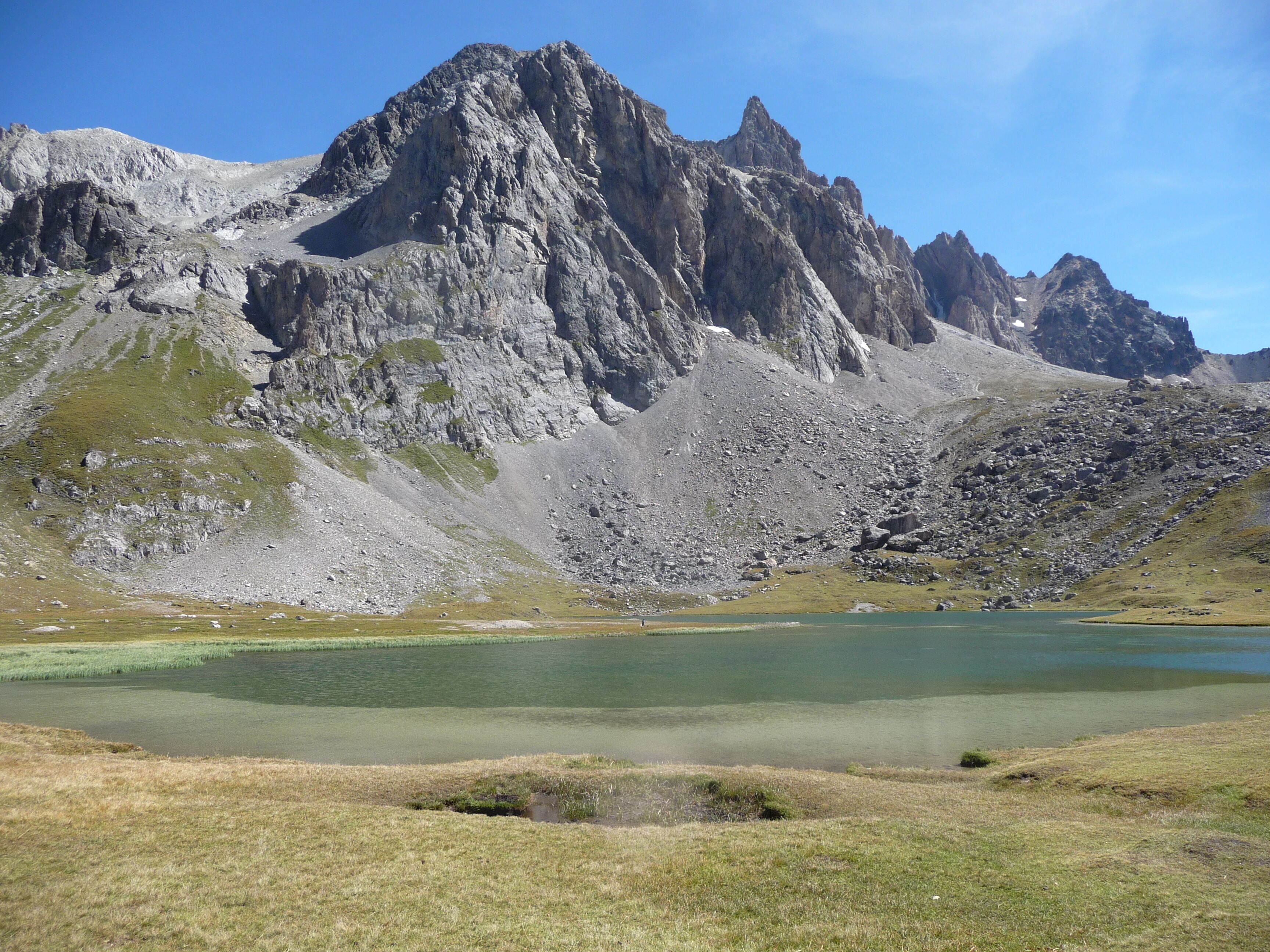Un paisaje montañoso con un lago y zonas cubiertas de hierba.